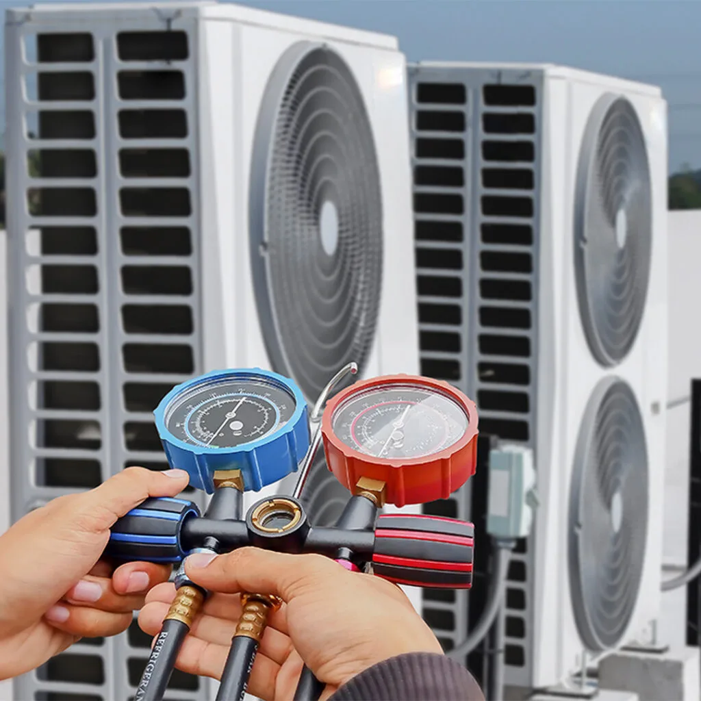 Hands holding HVAC manifold gauges to check pressure levels on outdoor AC units, used by a heating and cooling contractor near me.