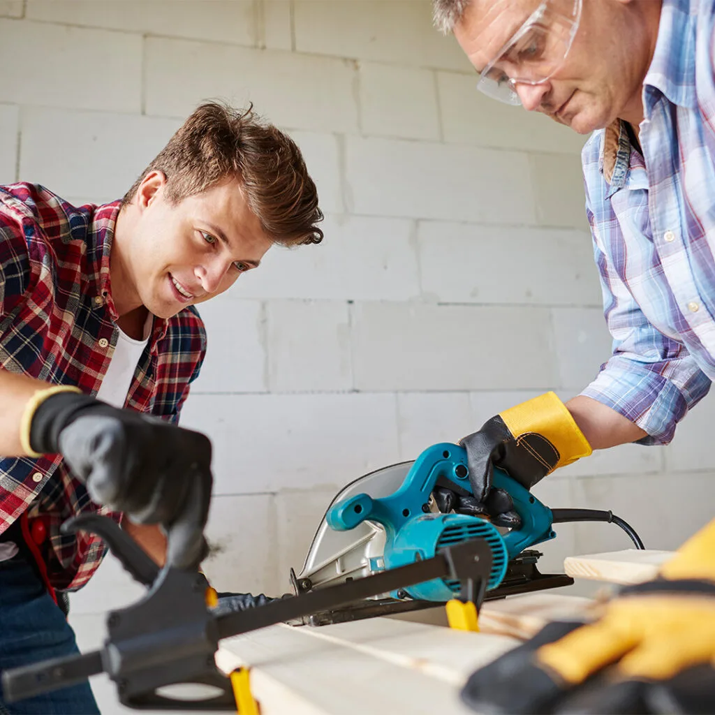 Two handymen using a circular saw to cut wood, demonstrating expert service from the best handyman near me for home repairs.