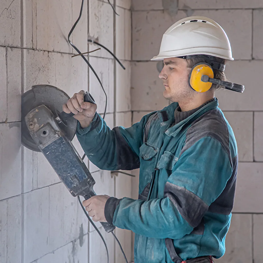 Contractor using a power grinder to cut into concrete blocks, suitable for masonry contractors near me focused on structural work.