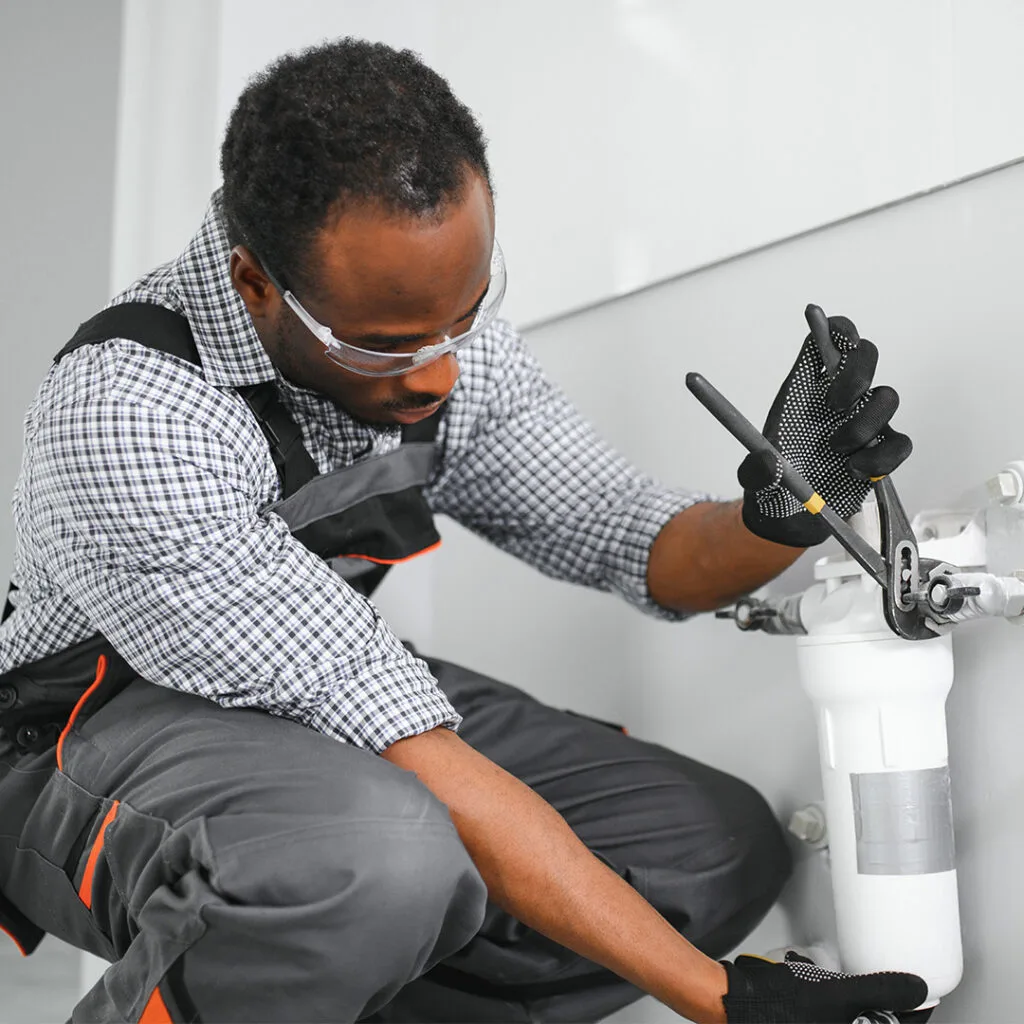 Plumber using a wrench to install or repair a water filtration system, illustrating emergency plumber near me services.