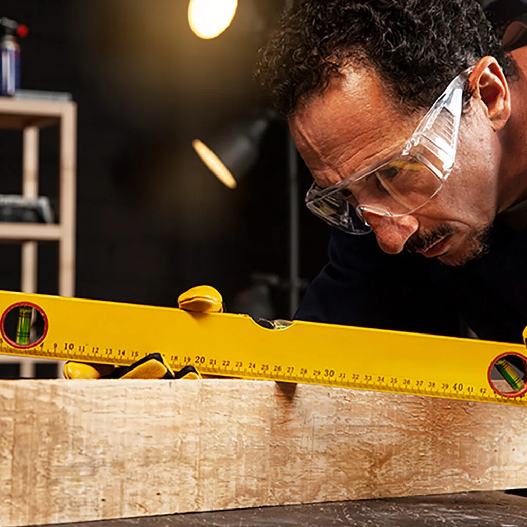 Carpenter near me using a spirit level to check precision on a wooden plank during a custom woodworking project.