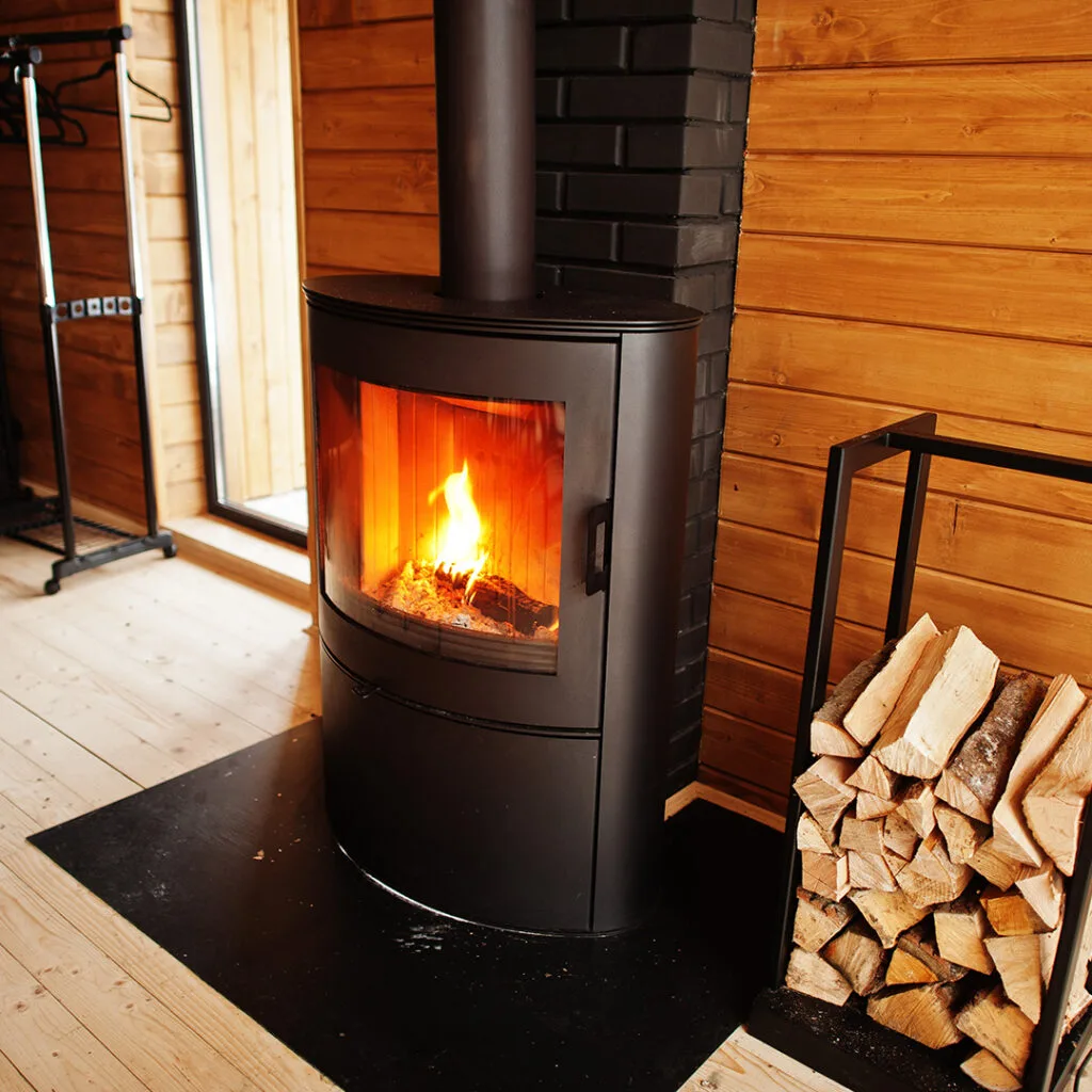 Modern wood-burning stove with a visible flame in a cozy cabin, representing safe fireplace use after a chimney sweep near me service.