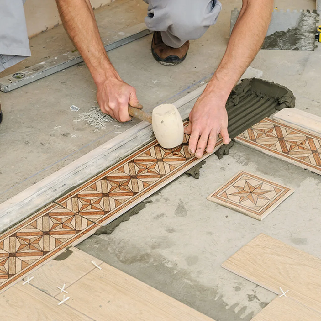 Flooring installers near me placing decorative wooden tiles with precision and securing them using a rubber mallet.