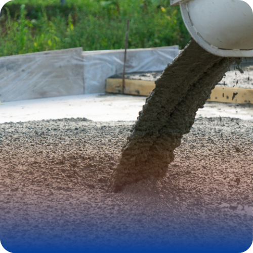 Fresh concrete being poured from a chute onto a construction site foundation.
