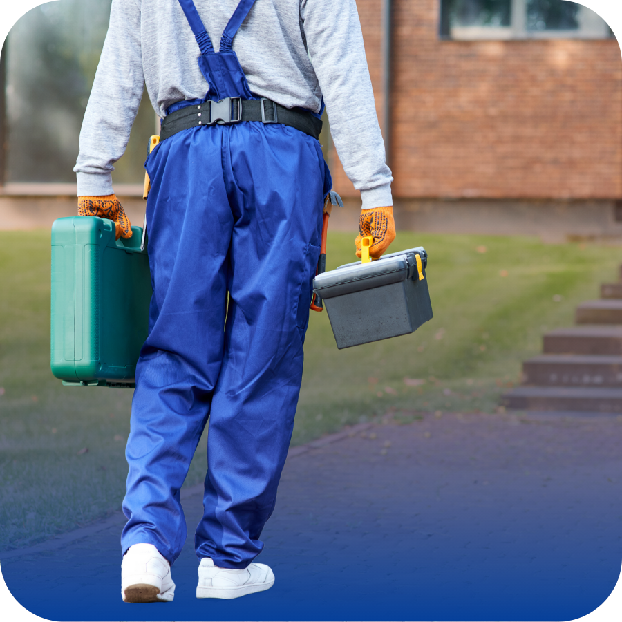 A man wearing overalls is speaking on a cell phone, looking focused and attentive in a casual setting.