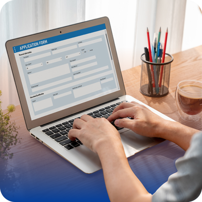 A person engaged in typing on a laptop, completing a form related to contractor directory applications.