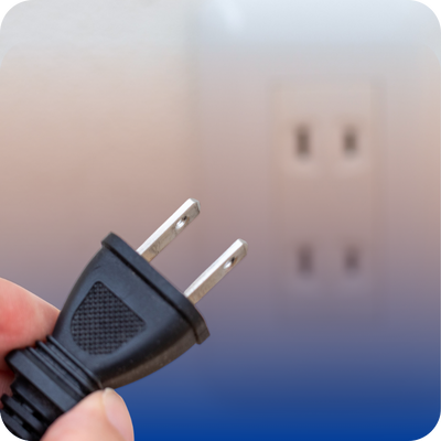 A person holds an electric plug against a blue background, symbolizing the message to disconnect appliances safely.