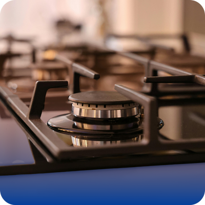 Close-up of a black burner on a stove top with a blue background, relevant to gas appliance ignition problems for homeowners.
