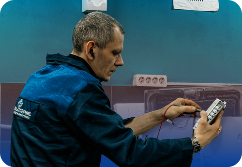 A man wearing a blue jacket working intently on a computer, illustrating the operations of emergency repair technicians.