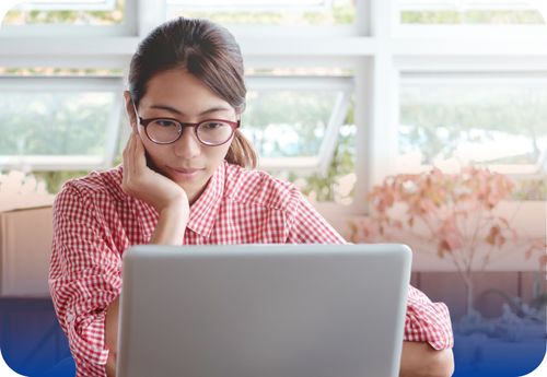 A woman in glasses sits at a table with a laptop, highlighting essential contractor checks often overlooked by homeowners.