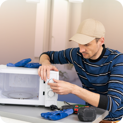 A man is fixing a microwave beside a table, showcasing home repair tips for homeowners looking for contractor help.