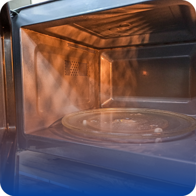 A microwave oven containing a plate, emphasizing the need for homeowners to report any unusual smells or sounds.