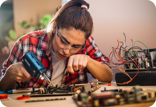 A woman using a drill to work on electronics, showcasing hands-on skills for home improvement projects.